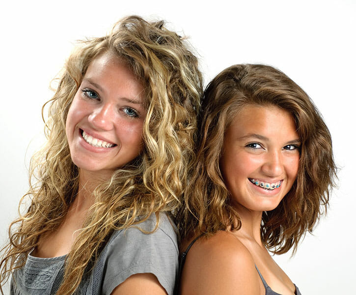 Backus Smiles, Clear and Metal Braces, Two sisters back to back smiling with braces