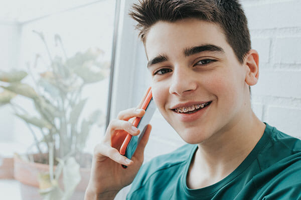 Backus Smiles, Comfort Care Instructions, Boy talking on the phone to the doctor about his braces